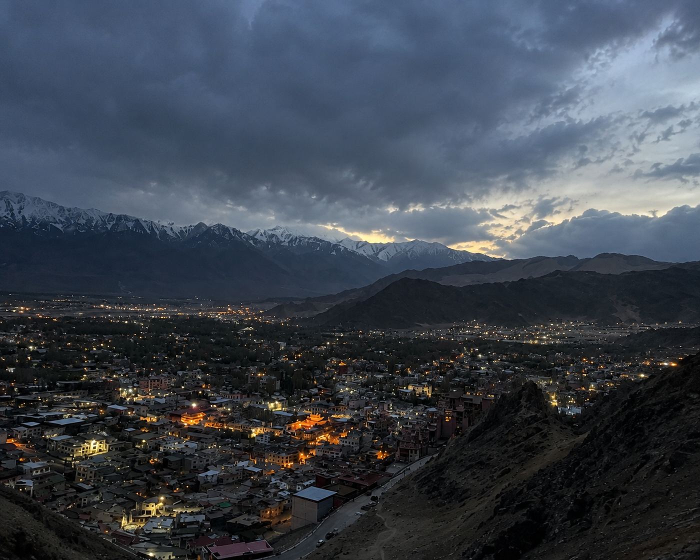 Leh town lit up at dusk below the snow-covered Stok range in Ladakh